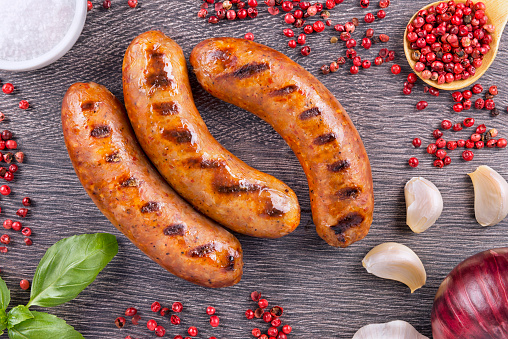 Grilled sausage with spices on a dark wooden background.