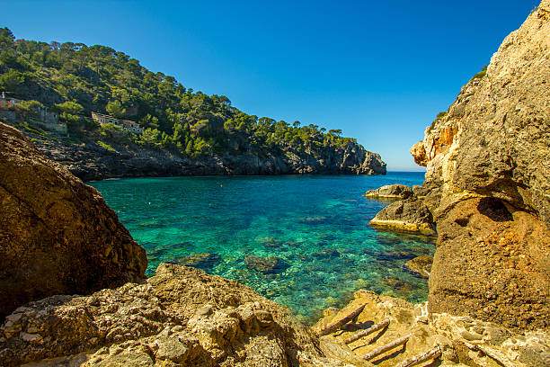 Panoramic Cala Deia tropic empty beach turquoise mediterranean Palma Mallorca Panoramic view from Cala Deia breathtaking mediterranean tropic empty beach 30 km from Palma de Mallorca seaside views of cala fornells mallorca stock pictures, royalty-free photos & images