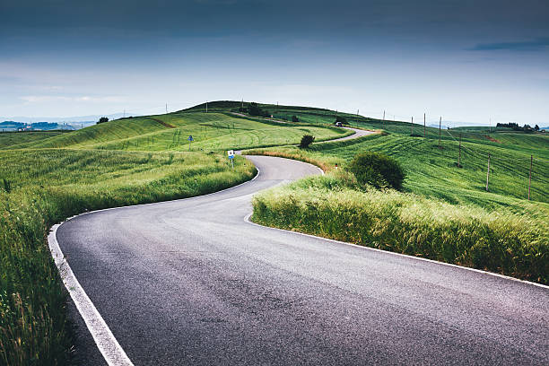 トスカーナの丘の上に曲がりくねった道 - country road ストックフォトと画像