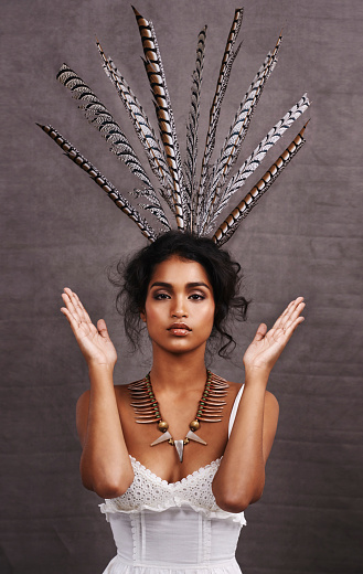 Cropped portrait of a stylish young ethnic woman posing with feathers in a studio