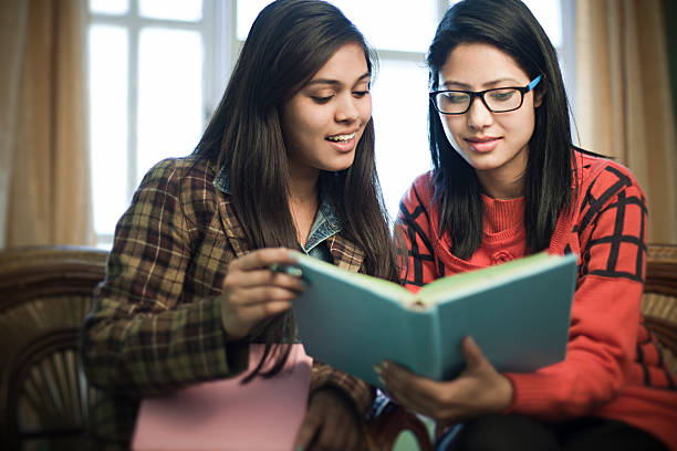 Late teen happy girl students studying a book together. stock photo