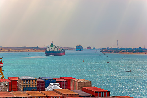 Industrial container ship passing through Suez Canal with ship's convoy, view on the bow from the captain bridge.