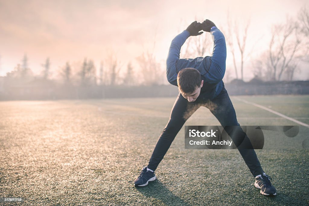 Handsome athlete warming up before jogging Cold Temperature Stock Photo
