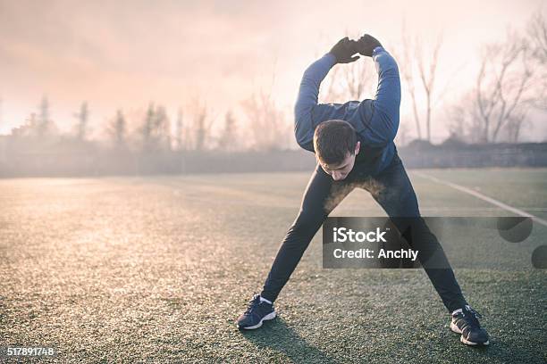 Handsome Athlete Warming Up Before Jogging Stock Photo - Download Image Now - Cold Temperature, Stretching, Autumn