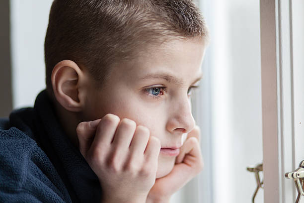 istock Pensive Boy Leans his Face on Hands at the Window 517895090