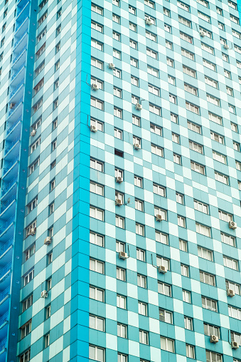 Multistoried turquoise skyscraper building façade with air-conditioners on wall. Moscow, Russia.