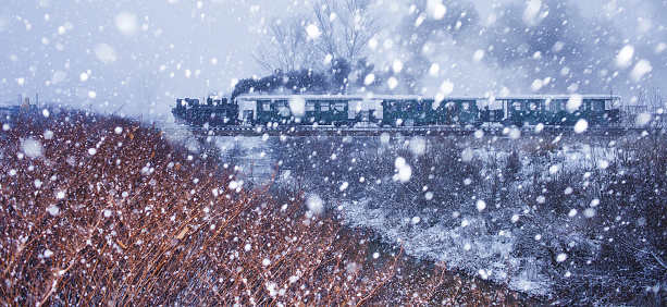 Old steam train in snow storm. Tourism in Europe. 