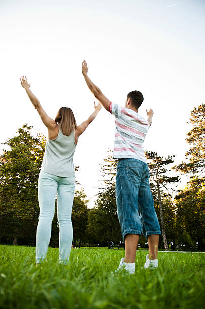 istock Couple Standing on Grass with Raised Arms 517896856