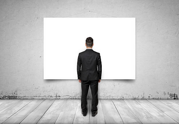 istock Back view of businessman looking at white empty canvas on 517897482