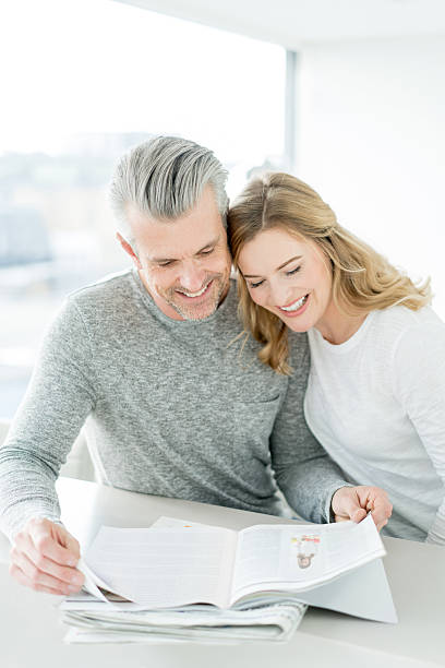 couple reading a magazine at home - for rent sign house sign happiness imagens e fotografias de stock