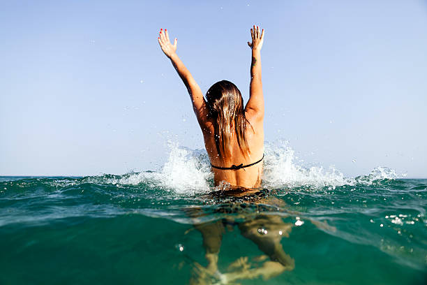 sexy girl swim sea waves hands up splash back view sexy bikini girl swim sea waves hands up jump splash in tropics on vacation back view wave jumping stock pictures, royalty-free photos & images