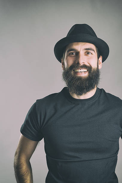 istock Laughing bearded hipster wearing t-shirt and hat looking at camera 517903066