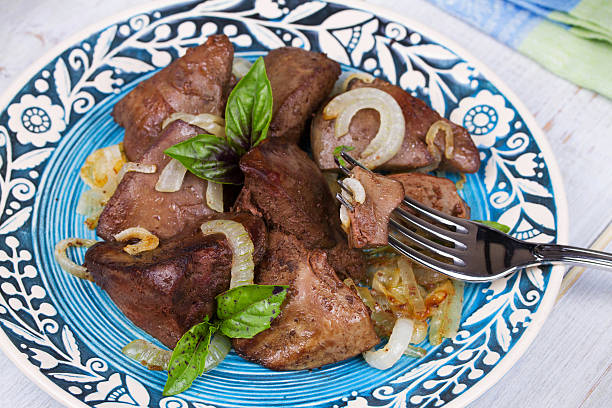 Sauteed liver with onions on blue plate, view from above, studio shotSauteed liver with onions on blue plate, view from above, studio shot