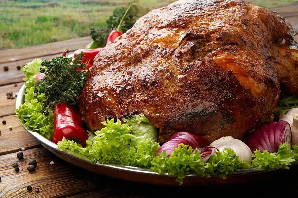 Restaurant food, roasted pork shoulder. Meat dish. Festive banquet dish, holiday dish. Catering. Served main dish, roasted pork with vegetables and herbs. Closeup at wooden rustic background.