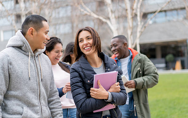 Happy group of students outdoors Happy group of multi-ethnic young students outdoors laughing and holding notebooks Studying Abroad stock pictures, royalty-free photos & images
