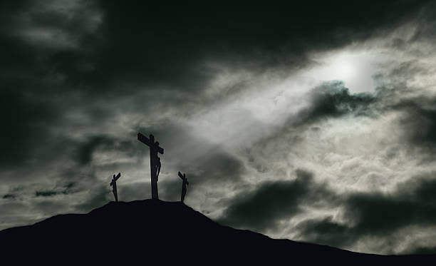 Crucifixion of Jesus on Golgotha With Copy Space A depiction of the crucifixion of Jesus Christ on a cross with 2 other robbers nearby on Calvary. The sky is darkened with rays of light breaking through the clouds onto the cross for drama. Concept of the death of Jesus on Good Friday and His resurrection on Easter Sunday. Horizontal orientation with copy space. the crucifixion photos stock pictures, royalty-free photos & images