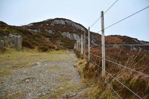 Pathway along a fence leading to a mountain
