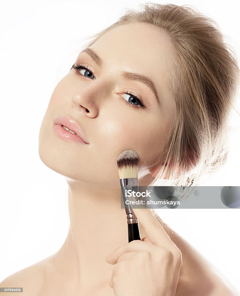 Portrait of young woman with make-up foundation brush Portrait of young woman with make-up foundation brush, apptying foundation.Close up blue eyes.Blond.Perfect skin Adult Stock Photo