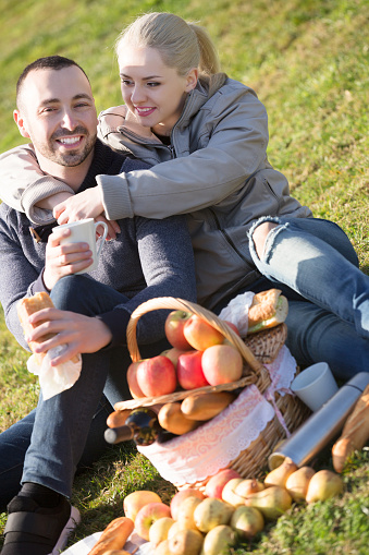 Smiling young spouses lounging in sunny spring day at picnic outdoors