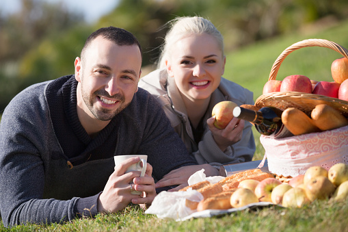 Portrait of happy young spouses lounging in sunny spring day at picnic outdoors
