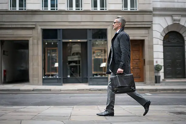 Successful senior business man walking down the street carrying a briefcase