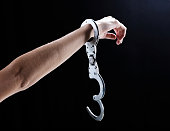 I'm free! Female hand wearing single, open handcuff.