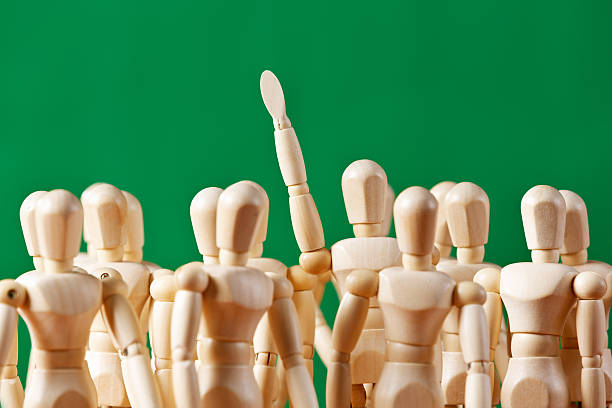 istock Standing out from the crowd: single puppet raises hand 517930207