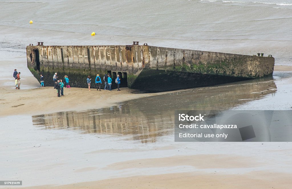 Arromanches les Bains - Normandia Arromanches les Bains, France - July 9, 2014: group of tourists through the remains of the means used by the American landing in Normandy on the beaches of the Bay of Arromanches where it is consumed the bloodiest battle in history, better known as D-Day Basse-Normandy Stock Photo