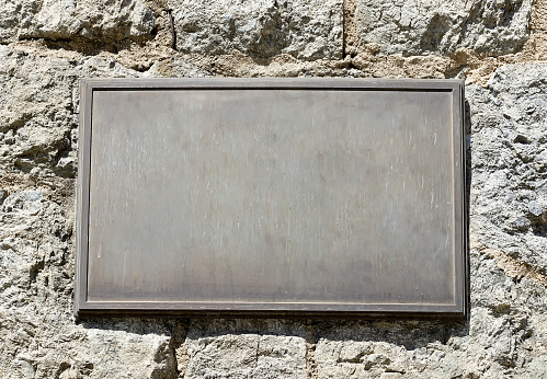 Metal plaque mounted on an old stone wall.