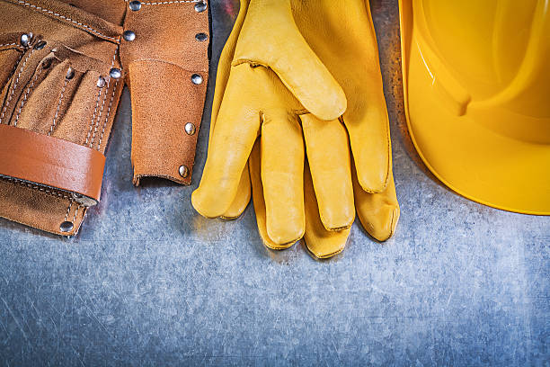 istock Yellow leather safety gloves tool belt hard hat on metallic 517937024