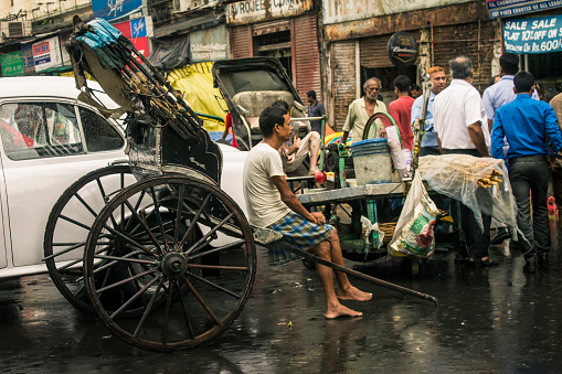Kolkata, India - June 1, 2014: A rickshaw puller sits on his wooden rickshaw waiting for customers in the streets of Kolkata, India.