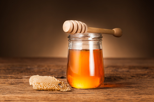 Honey pot preserved with honeycomb on wood background