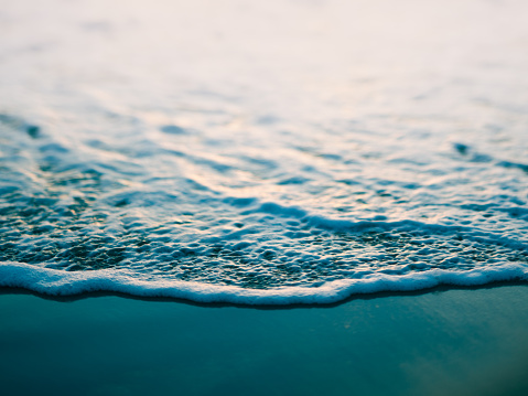 Macro toned horizontal photo of ocean and small wave on beach. Actual tilt/shift lens used to exaggerate blur.