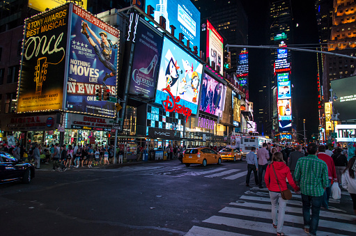 New York City, USA, August  15, 2013:Tourists at  Times Square at night, the famous location in New York city, full of people and cars and its neon light signs.