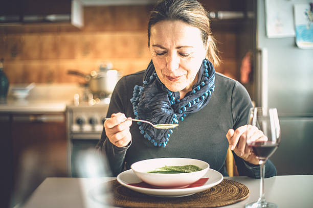 Mature woman eating soup stock photo