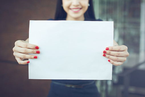 Half face of business woman holding an empty sign - ready to put text on