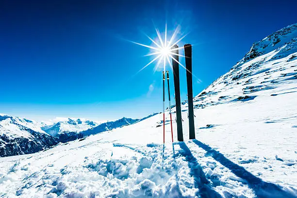 Skis and ski poles on top of ski resort against the sun. Taken by Sony a7R II, 42 Mpix.