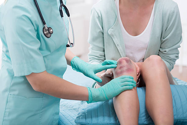 Woman with bruised knee Woman with bruised knee at doctor's office knee contusion bruised knee stock pictures, royalty-free photos & images