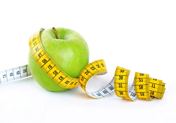 istock Diet concept, green apple wrapped with measuring tape 517971794