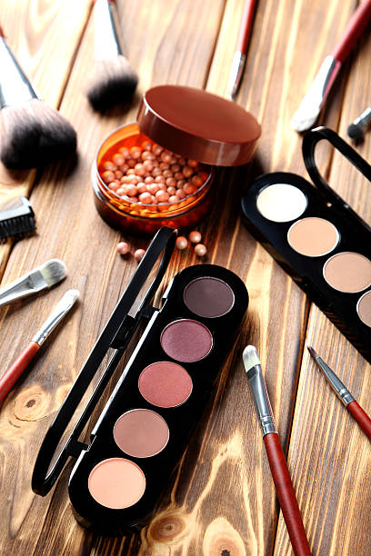 istock Makeup brush and cosmetics on brown wooden table 517972360