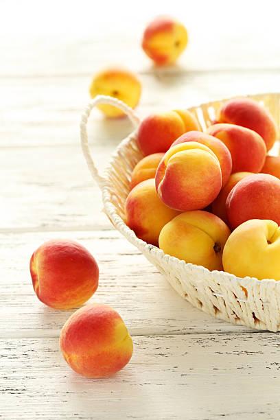 istock Fresh apricots in basket on a white wooden background 517972474