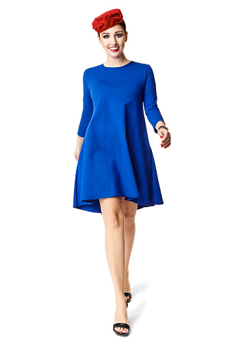 Studio shot of attractive walking woman in blue dress.
