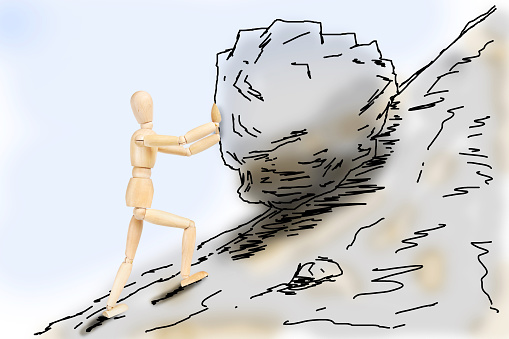 Man pushing a stone up to the mountain slope. Abstract image with a wooden puppet