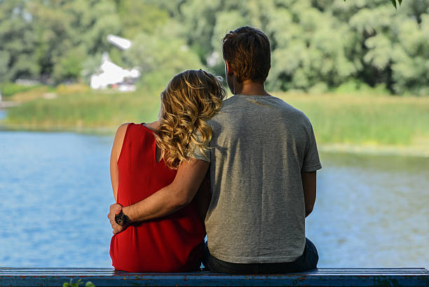 istock Young  couple sitting on the bench hugging. River background 517987648