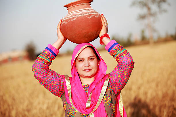 istock Farmer women carrying water pot on Her Head 517989440