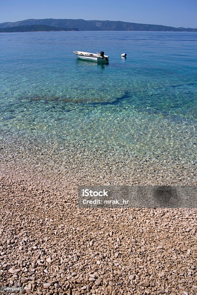Little boat on pebble beach Pebble beach in Farska bay on Island Brac in Croatia Adriatic Sea Stock Photo