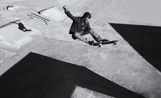 A black and white shot of a skateboarder doing tricks at a skatepark