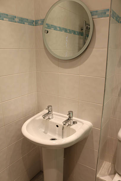 istock Image of pedestal sink, circular mirror, modern, white tiled bathroom 517994670