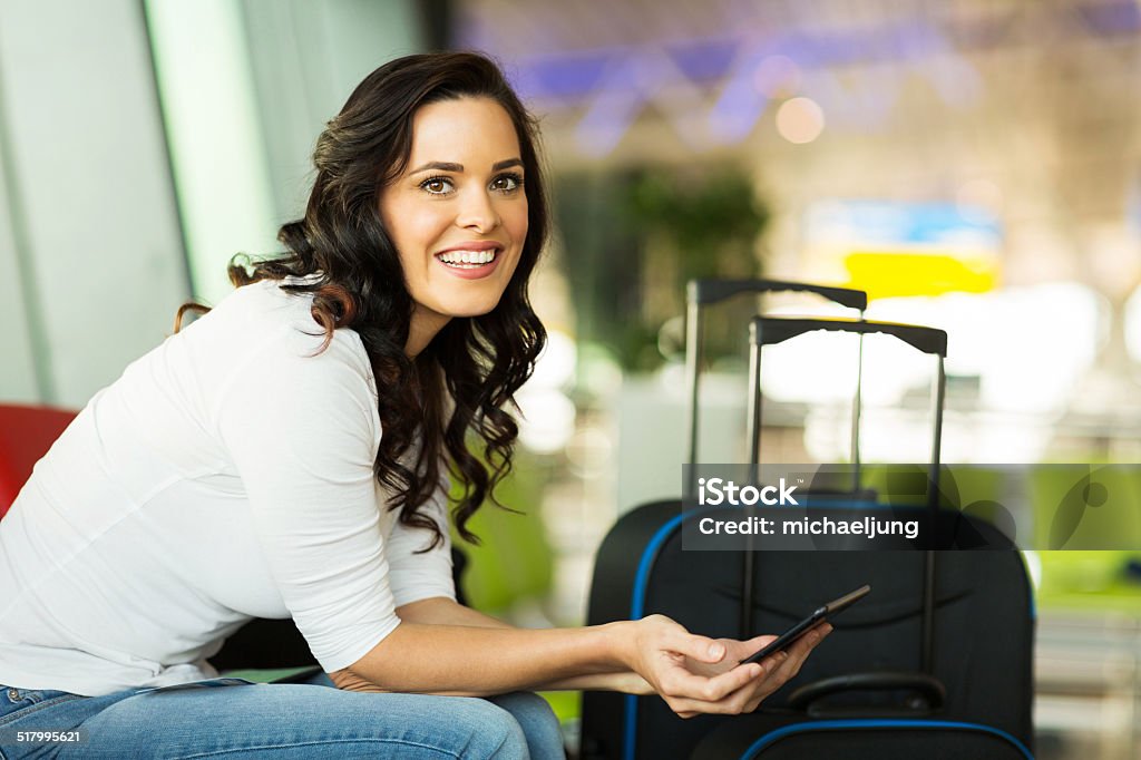 female traveller using tablet computer smiling female traveller using tablet computer while waiting for her flight at airport Digital Tablet Stock Photo