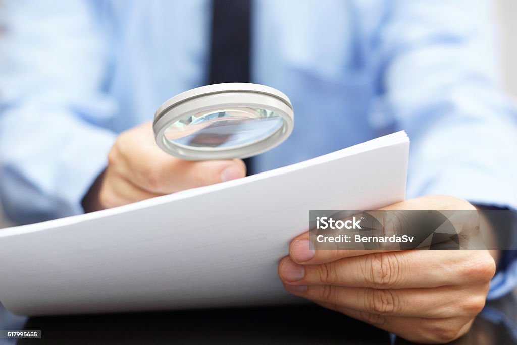 Businessman looking through a magnifying glass to contract Magnifying Glass Stock Photo